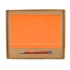 An orange notebook and a metal pen are neatly placed inside a simple brown cardboard box. The notebook is closed with an elastic band, and the pen has a metallic finish with orange accents.