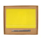 A yellow notebook with an elastic band and a silver pen are neatly placed in a brown cardboard box against a white background.