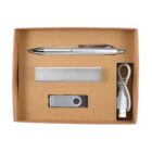 A cardboard gift box contains a silver pen, a rectangular metallic keychain, a silver USB flash drive, and a white USB cable.