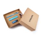 An open kraft-colored box featuring a blue pen, USB drive, business card holder, and keychain inside, all branded with Regal Legal Commercial in blue and white. The box lid has the same logo printed.