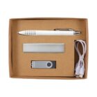 A cardboard gift box containing a white pen, a silver USB flash drive, a rectangular gray power bank, and a white charging cable with two connectors.