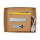 A brown cardboard box contains a yellow pen, a silver business card holder, a USB flash drive, and a white USB cable with dual connectors neatly arranged inside.