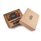 A brown gift box with branding contains a power bank with a colorful dotted pattern, a pen, and a USB drive. The box is partially open, displaying the contents neatly arranged inside.