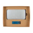 A cardboard box contains a silver rectangular object with black edges and a blue USB flash drive. The objects are neatly arranged within the box.
