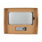 Cardboard box containing a silver metal power bank and a gray USB flash drive. The power bank is larger and rectangular, while the flash drive has a swivel design. Both are neatly arranged inside the box.