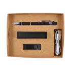 A brown box containing a black pen, a rectangular black device, a black USB flash drive, and a white USB cable. The items are neatly arranged in individual compartments within the box.