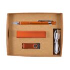 A cardboard box containing an orange pen, an orange power bank, an orange USB flash drive, and a white USB charging cable. The items are neatly arranged in separate compartments.