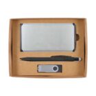 A gift set inside a cardboard box containing a silver business card holder, a black pen, and a silver USB flash drive. The items are neatly arranged with the card holder on top and the pen and USB drive below.