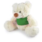 A fluffy white teddy bear with a brown nose, pink inner ears, and a green bib-like fabric around its neck is sitting upright.