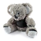 A gray plush koala toy sits with a black patch across its chest. Its soft, furry texture and large, fluffy ears give it a cuddly appearance. The toy has white accents on its paws and ears.
