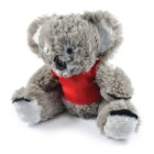 A fluffy, gray stuffed koala bear wearing a red shirt is sitting upright. The toy has large ears, a black nose, and black eyes, giving it a cute appearance against a white background.