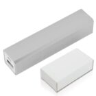A rectangular portable power bank charger in a light gray color with a USB port is shown next to a small, closed white box.