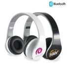 Two wireless Bluetooth headphones, one black and one white, with logos on each earcup. The white headphones have the Dimantium logo, and the black ones have the Hybrid Core logo. The Bluetooth symbol is visible in the top-right corner.