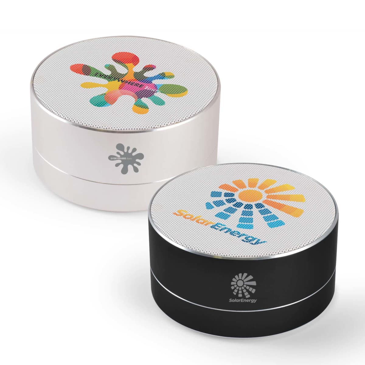 Two cylindrical Bluetooth speakers, one white and one black, each with colorful logo designs on top. The white speaker features a multicolored splash logo, while the black one displays a sunburst pattern with the text Solar Energy.
