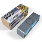 Cardboard packaging for a product labeled Adventure Awaits, featuring a smiling person in outdoor gear. The box reads BEGIN YOUR ADVENTURE and has a sleek, textured design with mountain imagery.