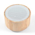 A small cylindrical speaker with a bamboo exterior and a silver mesh top.
