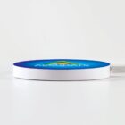 Round, sleek wireless charger with blue top and white sides on a white surface.