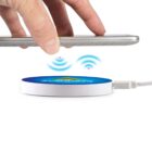 Hand placing a phone on a wireless charger with a glowing blue light.