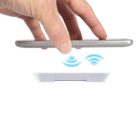 Hand holding smartphone hovering over a wireless charging pad emitting signal waves.