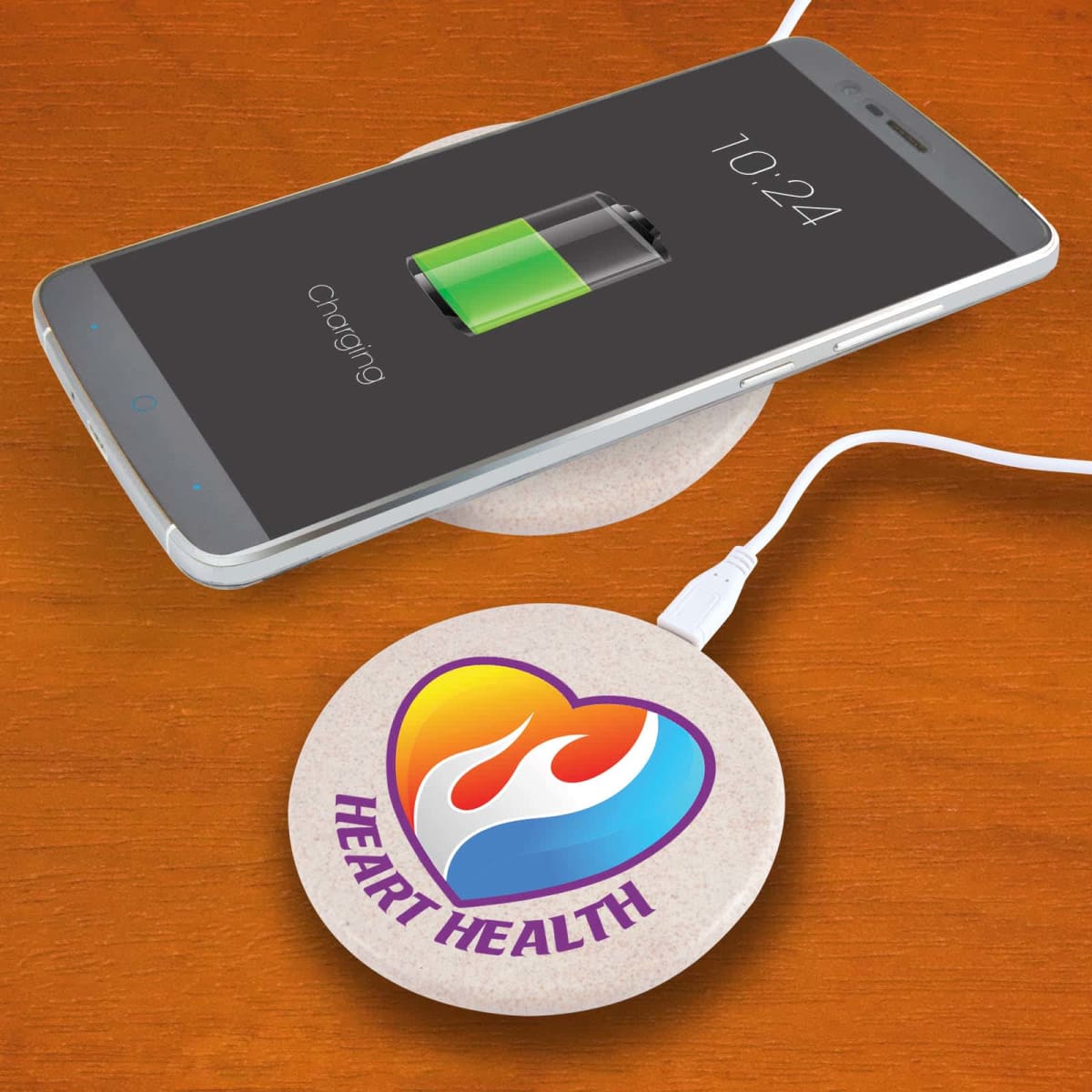Phone charging wirelessly on a pad with a Heart Health logo.