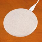 White circular warming plate with a USB plug on a wooden surface.