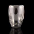Transparent double-walled glass cup on a reflective black surface.