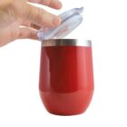 Hand opening lid of a red insulated tumbler cup against white background.