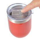 Finger touching lid of a red tumbler with a clear sliding cover.