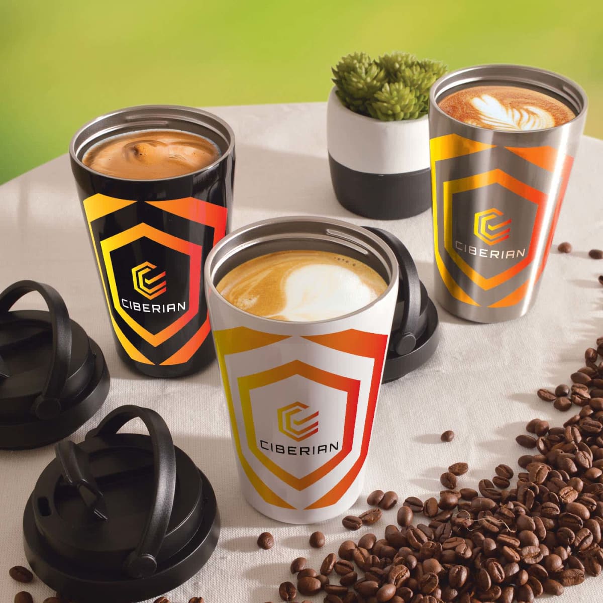 Three branded coffee cups with lids, surrounded by coffee beans on a table.