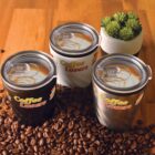 Three coffee cups on coffee beans with a succulent in the background.