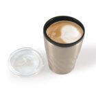 A latte with latte art in a stainless steel travel mug, next to a clear lid.