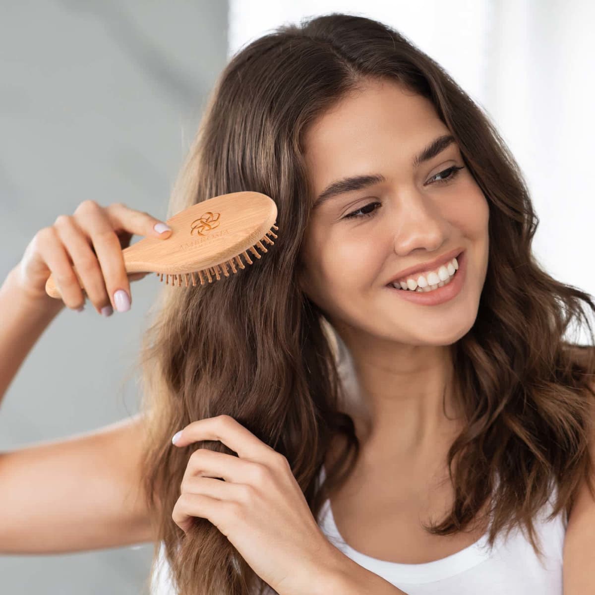 Smiling woman brushing her long brown hair with a wooden brush.
