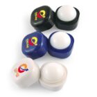 Three lip balm containers in black, blue, and white, open to reveal the balm inside.