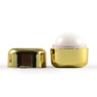 Gold lip balm container with cap off, revealing dome-shaped balm.