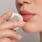Person applying lip balm from a circular container.