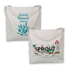Two white tote bags with designs: one with Coral Shores Care, the other with Sprout Community Gardens.
