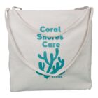 Beige canvas tote bag with Coral Shores Care and a teal coral graphic printed on it.