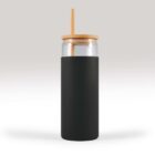 Glass tumbler with a black sleeve, wooden lid, and straw on a gray background.