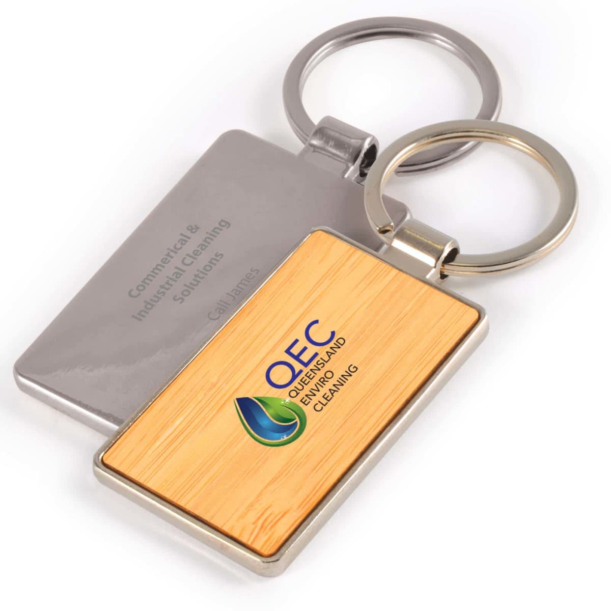 Two rectangular keychains, one with a wooden texture and QEC Queensland Cleaning logo, the other plain metal.