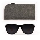 Black sunglasses with dark lenses placed below a gray felt case on a white background.