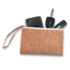 Cork wristlet pouch with a smartphone, car key, and green item partially exposed.
