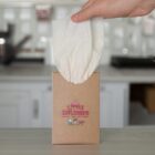 Hand pulling a tissue from a box labeled Little Explorers on a kitchen counter.
