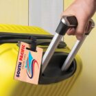 Hand pulling a yellow suitcase with a South Pacific Cruise Lines luggage tag.