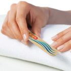 Person holding a nail file over a white towel, preparing to manicure nails.