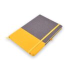 A closed gray and yellow notebook with a yellow elastic band and ribbon bookmark on a white surface.