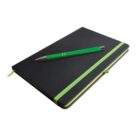 A black notebook with green edges and an elastic band lies closed on a white surface. A green pen with silver accents rests diagonally on top of the notebook.