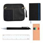 Flat lay of stationery items on a white background, including a black zippered pouch with mesh pocket, black notebook with blue elastic, black ballpoint pen, white ruler with metric markings, and a box of colored pencils.