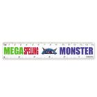 A white ruler with a blue monster face in the center. The words MEGA SPELLING MONSTER are written across it, with MEGA in green, SPELLING in red, and MONSTER in blue. The ruler shows measurements in centimeters and inches.