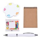 A flat lay image of a notepad, a pen, a packet of colorful jelly beans, and cloud-shaped sticky notes. The notepad has a brown cover and a spiral binding at the top. The pen is white and silver.