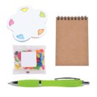 A set of items including a flower-shaped sticky note pad with colored tabs, a small spiral notepad with a brown cover, a packet of colorful jelly beans, and a green pen with a silver clip, arranged on a white background.